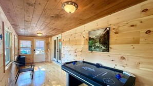Una habitación con suelo de madera, una mesa de billar, una silla y un cuadro en la pared.