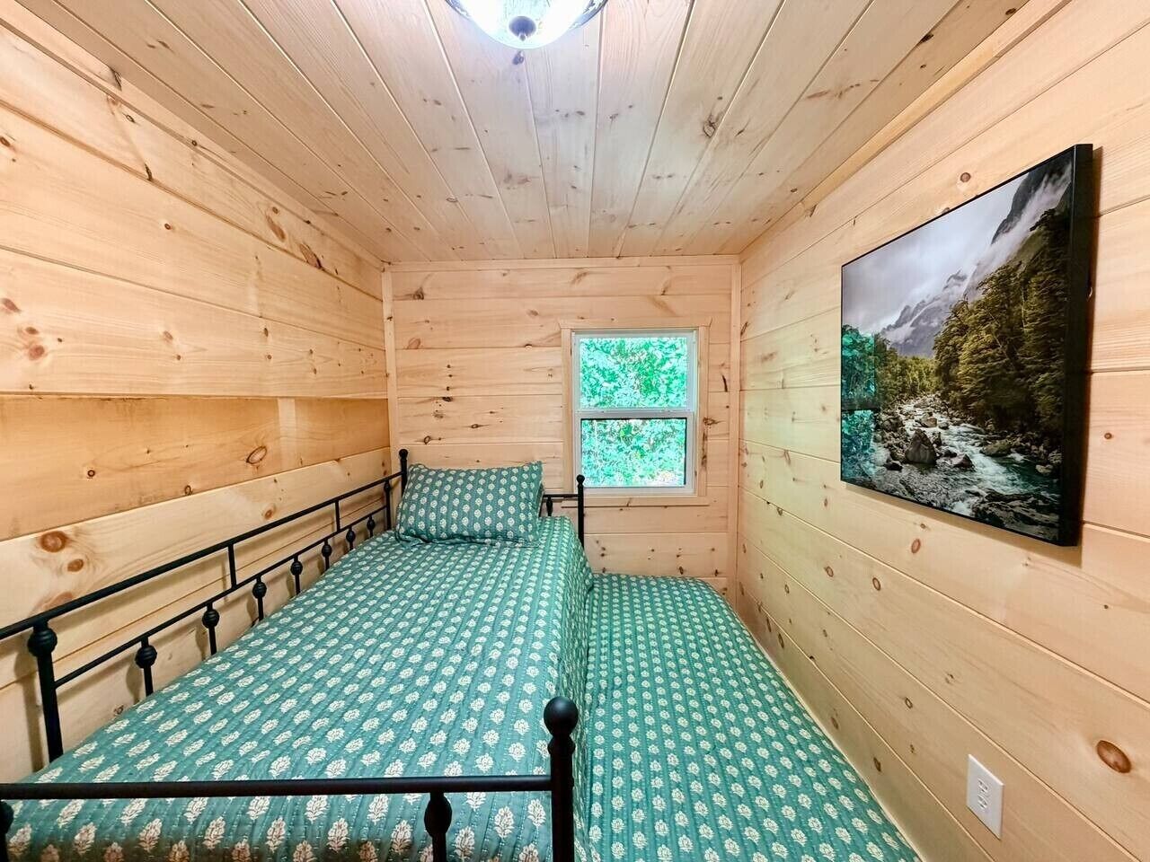 Een houten kamer met twee bedden, een raam en een televisie aan de muur.