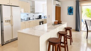 A modern kitchen with a central island, bar stools, a refrigerator, and a coffee maker. - Charming 2-bedroom apartment with AC in Old City Cartagena de Indias (Cartagena de Indias)