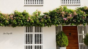 A building facade with white railings, a wooden door, and a planter with a shrub. - Charming 2-bedroom apartment with AC in Old City Cartagena de Indias (Cartagena de Indias)