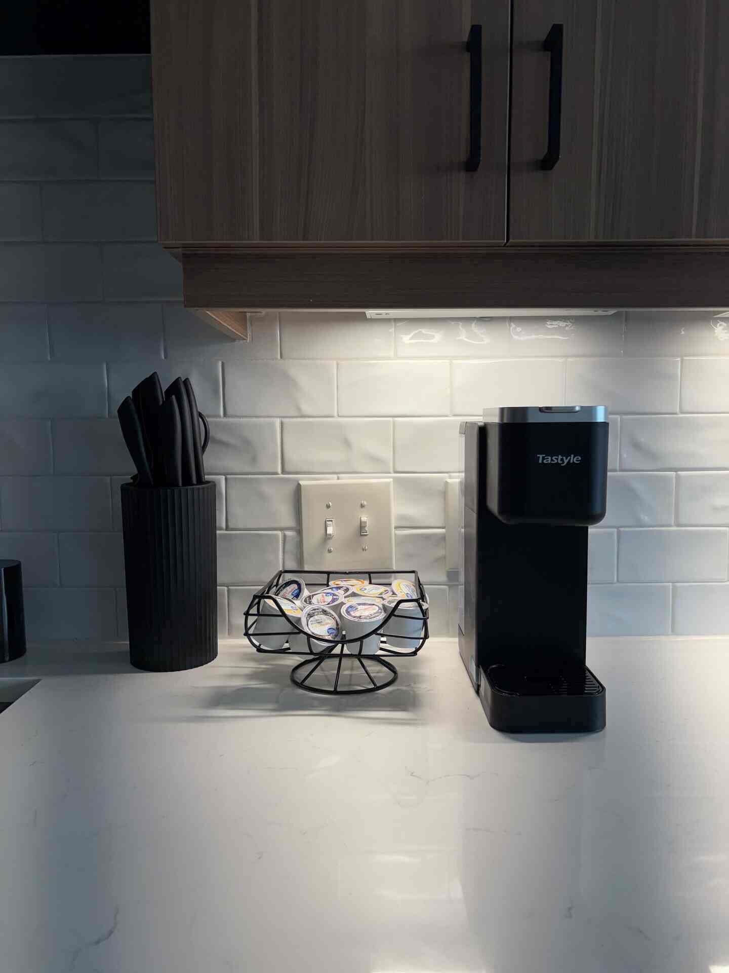 Une cuisine équipée d’une machine à café, d’un porte-couteaux et d’un récipient à yaourt sur le plan de travail.