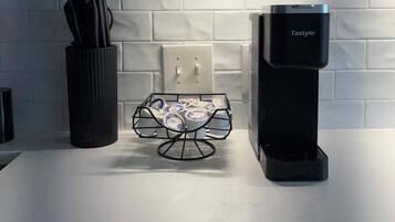 Une cuisine équipée d’une machine à café, d’un porte-couteaux et d’un récipient à yaourt sur le plan de travail.