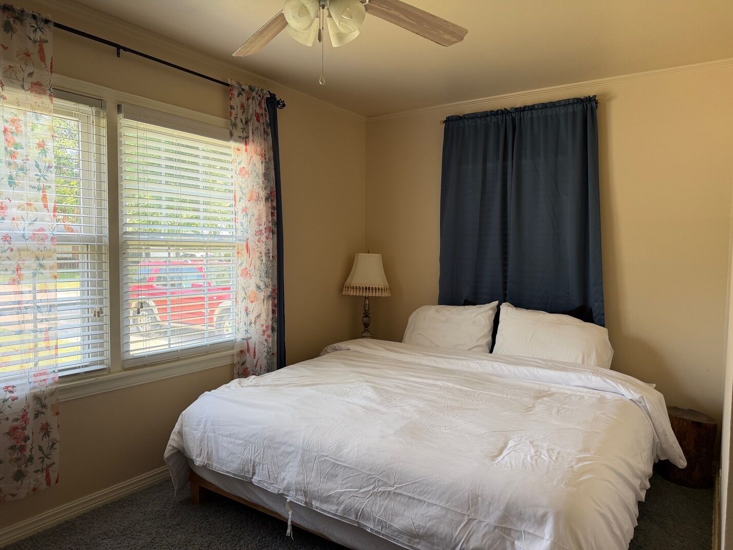 Une chambre à coucher avec un lit, une table de chevet, une lampe et un ventilateur de plafond.