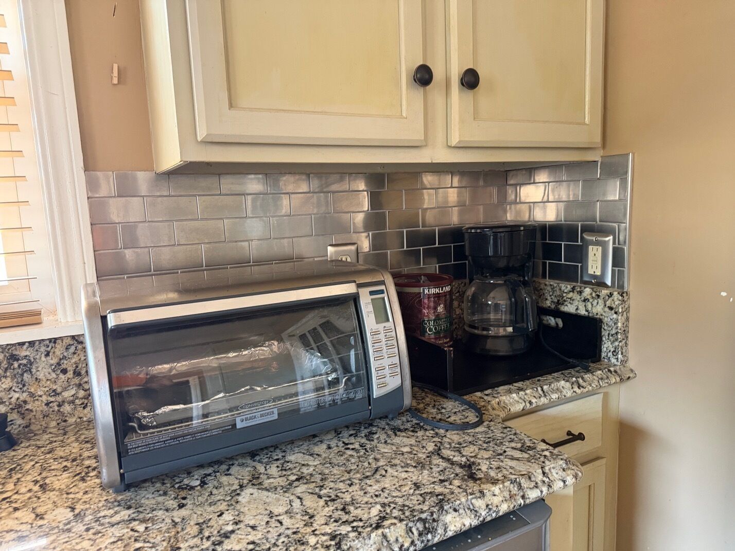 A kitchen with a built-in microwave, coffee maker, and granite countertop.