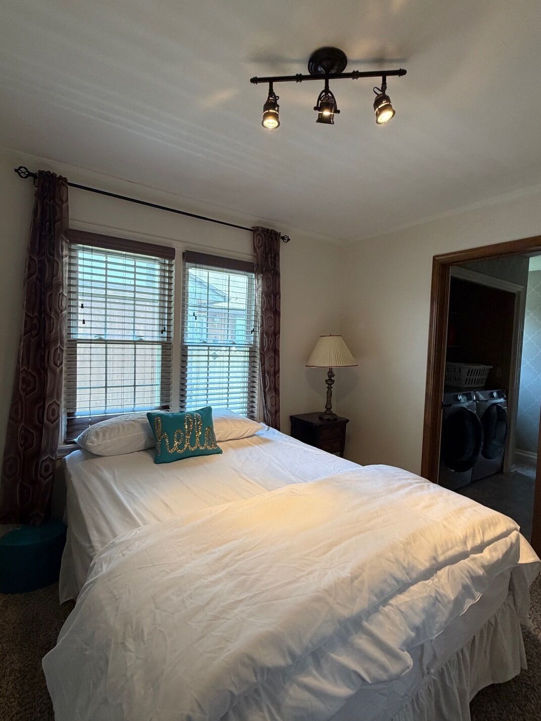 A bedroom with a bed, a nightstand, a lamp, and a window with curtains.