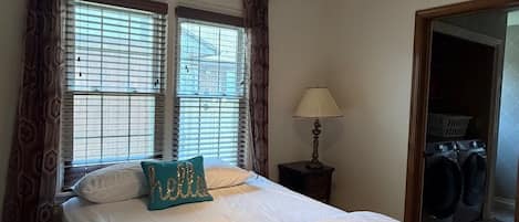 A bedroom with a bed, a nightstand, a lamp, and a window with curtains.