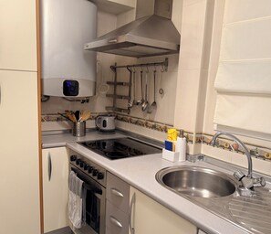 A kitchen with stainless steel appliances, a sink, and a variety of utensils hanging on the wall. - A 3 minute walk from the beach
La Piragua Accommodation (Torre del Mar)