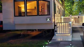 A mobile home with a large windowed front section, a visible number '15', and a gated entrance.