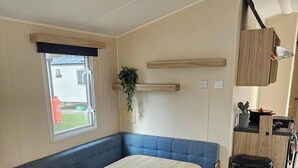 A compact RV interior with a dining table, seating area, and kitchenette. - Haggerston Castle Caravan Hire West Lawn (Berwick-upon-Tweed)