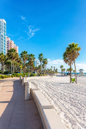 A beachfront promenade with palm trees, a sandy beach, and a row of buildings in the background. - The Lincoln Luxe Studio• Private Retreat • Midtown • Downtown • Stadium  (Tampa)
