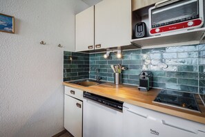 A compact kitchen with a dishwasher, a toaster, and a kettle on the countertop. - Résidence les Eterlous (Les Belleville)
