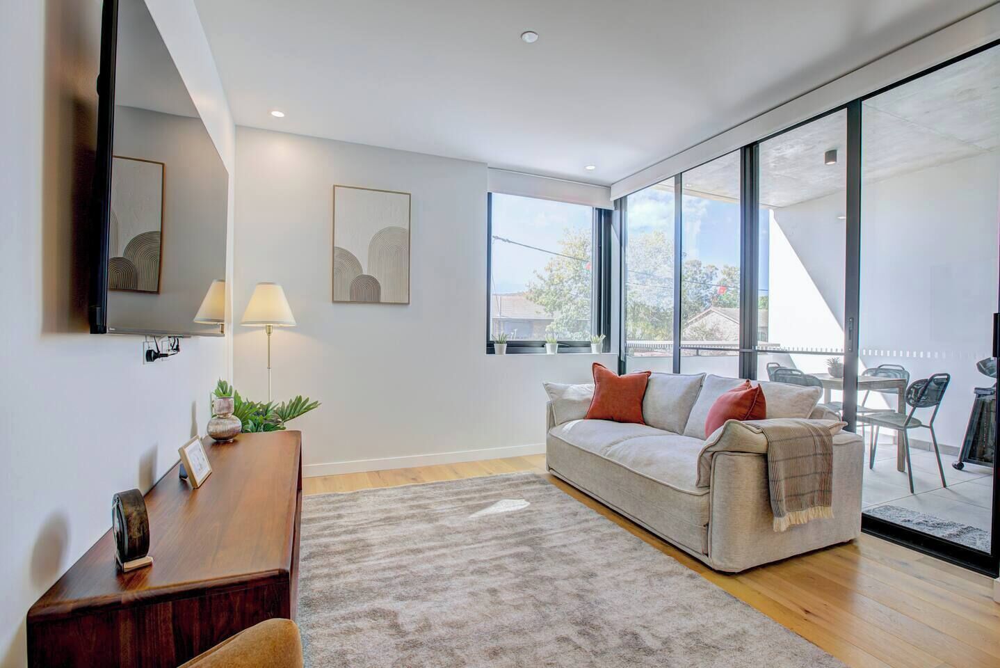 A modern living room with a sofa, a coffee table, and a TV mounted on the wall.