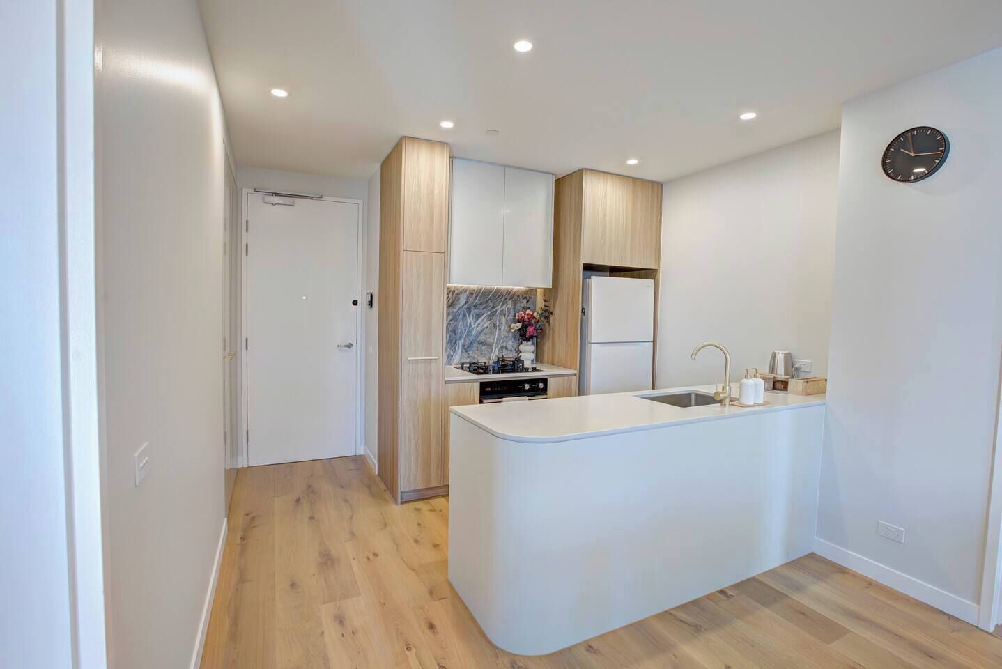 A modern kitchen with a central island, built-in appliances, and a wooden floor.