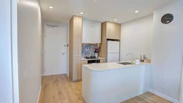 A modern kitchen with a central island, built-in appliances, and a wooden floor.