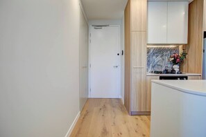 Ein schmaler Flur führt zu einer Küche mit Holzausstattung und einer weißen Tür.