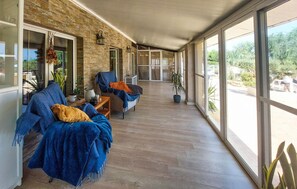 Eine überdachte Veranda mit zwei Sofas, einem kleinen Tisch und Topfpflanzen.