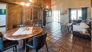 A dining area with a stone wall, wooden table, and chairs. - Gorgeous home in Dolores (Dolores)