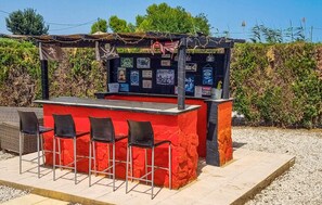 Eine Bar im Freien mit einer roten Theke und vier schwarzen Stühlen.