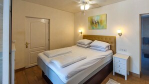 A hotel room with a bed, a bedside table, a ceiling fan, and a painting on the wall. - Gorgeous home in Dolores (Dolores)
