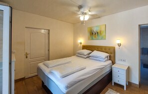 Ein Hotelzimmer mit einem Bett, einem Nachttisch, einem Deckenventilator und einem Bild an der Wand.