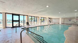 Une piscine intérieure avec des parois en verre transparent, un poste de surveillance pour les sauveteurs et un interrupteur d’arrêt d’urgence pour le spa.