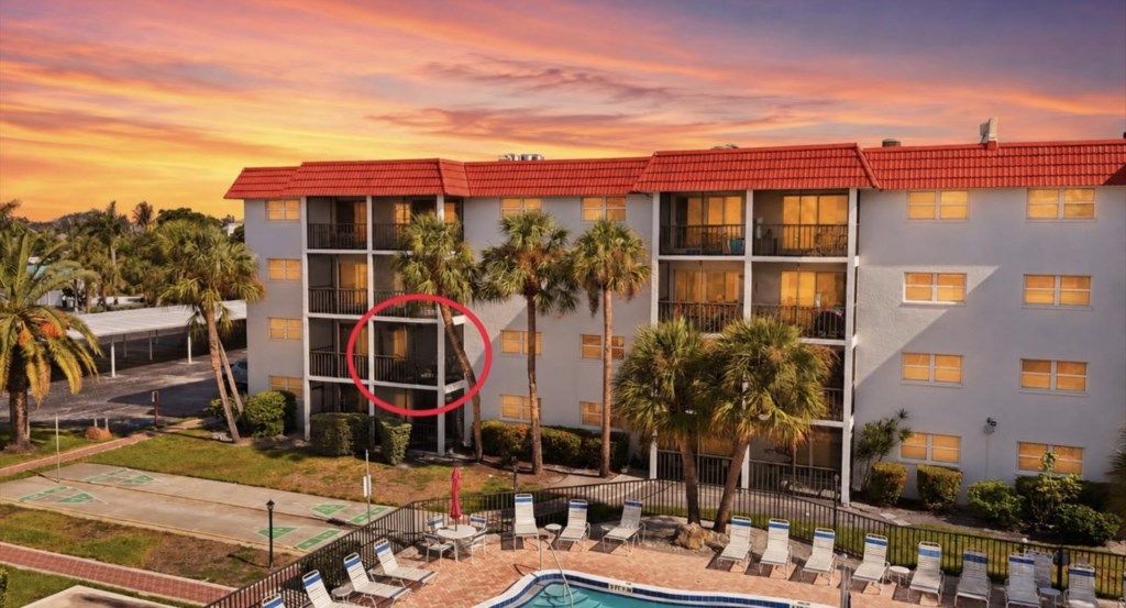 A hotel with multiple floors, a swimming pool, and palm trees.