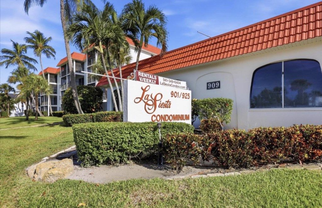A sign for La Fiesta Condominium with a contact number and website.