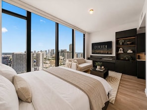 A modern bedroom with a large bed, a seating area, and a city view. - Executive Suite At The E11EVEN Residences (Miami)