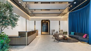A modern lobby with a reception desk, seating area, and a large blue curtain. - Executive Suite At The E11EVEN Residences (Miami)