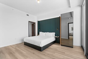 A modern bedroom with a large bed, a dark green headboard, a nightstand, and a large mirror. - E11EVEN 48th Floor | Bay Views & Rooftop Pool (Miami)