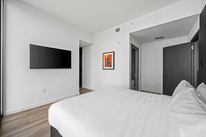 A modern bedroom with a large bed, a flat-screen TV mounted on the wall, and a framed artwork on the wall. - 48th Floor E11EVEN 2BR Bay Views ELITE Amenities (Miami)