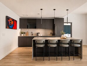 A modern kitchen with a central island, bar stools, and pendant lighting. - 48th Floor E11EVEN 2BR Bay Views ELITE Amenities (Miami)
