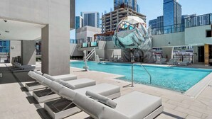 A rooftop pool with lounge chairs, a unique sculpture, and a city skyline in the background. - Stunning E11EVEN Residences Suite Rooftop Pool (Miami)