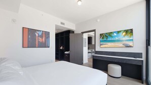 A modern hotel room with a bed, a desk, a chair, a small stool, a wardrobe, and a painting of a beach scene. - Stunning E11EVEN Residences Suite Rooftop Pool (Miami)