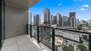 Ein Balkon mit Blick auf die Stadtlandschaft, darunter Hochhäuser und Baukräne.