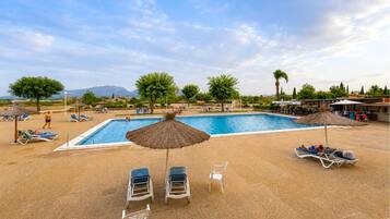 Zona de piscina con sillones de playa y sombrillas.