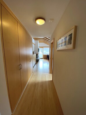 Ein Flur mit Holzboden, einer Deckenleuchte und einem gerahmten Bild an der Wand.