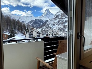 Un balcon offrant une vue sur des montagnes enneigées et un ciel dégagé.