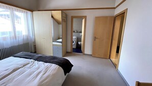 A bedroom with a bed, a wardrobe, a mirror, and a door leading to a bathroom. - Luxury Moments Begin, Wallis 1077 (Wallis)