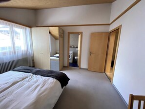 Ein Schlafzimmer mit einem Bett, einem Kleiderschrank, einem Spiegel und einer Tür zu einem Badezimmer.