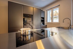 A modern kitchen with a built-in stove, a stainless steel sink, and a window providing natural light. - Breathtaking Luxury Stay, Wallis 1079 (Wallis)
