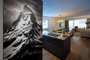 A modern kitchen with a central island, a dining area with a chandelier, and a living room with a sofa and a coffee table. - Breathtaking Luxury Stay, Wallis 1079 (Wallis)