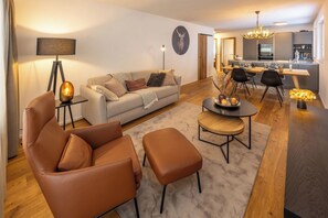 A modern living room with a sofa, two armchairs, a coffee table, and a dining area with a table set for four. - Breathtaking Luxury Stay, Wallis 1079 (Wallis)
