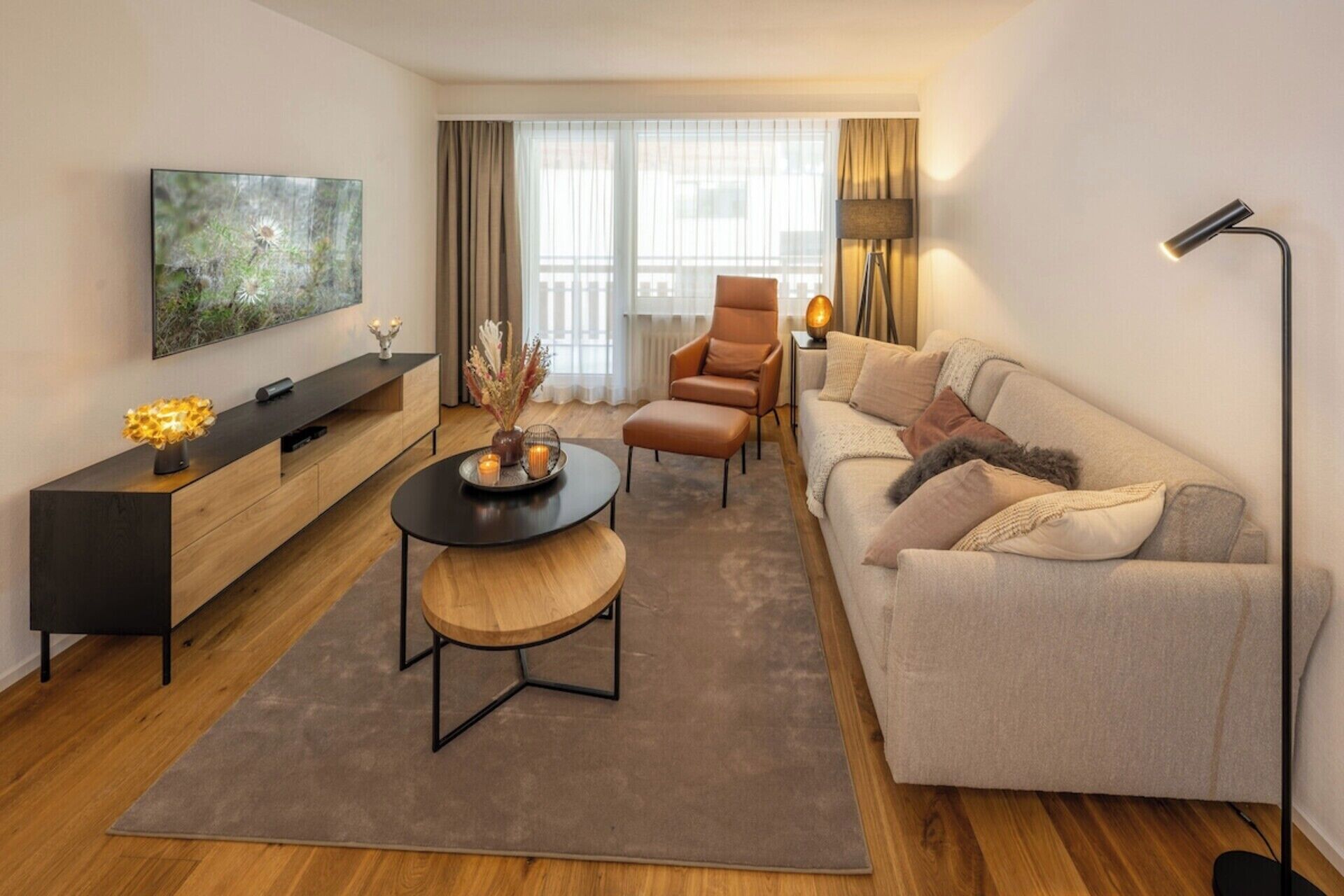 Una sala de estar moderna con un sofá, una mesa de centro, un televisor y una lámpara.