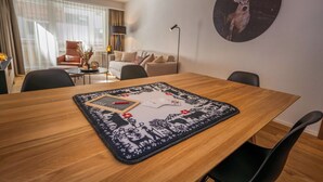 A hotel room with a dining table, chairs, a sofa, a lamp, and a wall-mounted picture of a deer. - Breathtaking Luxury Stay, Wallis 1079 (Wallis)
