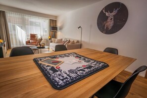A hotel room with a dining table, chairs, a sofa, a lamp, and a wall-mounted picture of a deer. - Breathtaking Luxury Stay, Wallis 1079 (Wallis)