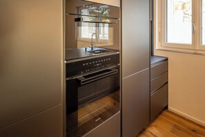A compact kitchen with a built-in oven and a window. - Breathtaking Luxury Stay, Wallis 1079 (Wallis)