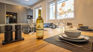 A dining table set with a bottle of wine, glasses, and plates in a modern kitchen with large windows. - Breathtaking Luxury Stay, Wallis 1079 (Wallis)