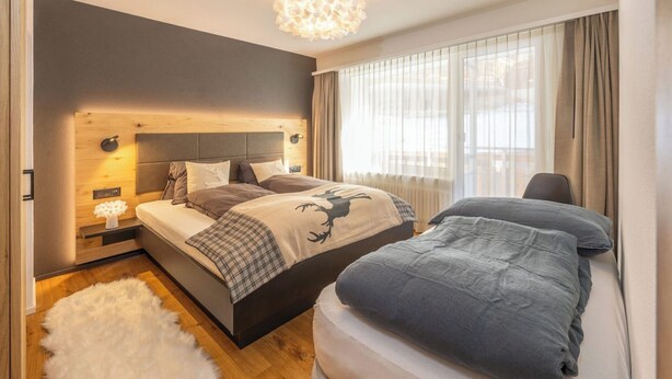A modern bedroom with a large bed, bedside tables, a fluffy rug, and a chandelier. - Breathtaking Luxury Stay, Wallis 1079 (Wallis)