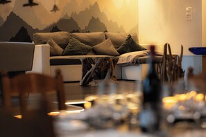 Ein modernes Wohnzimmer mit einer Couch, einem Couchtisch mit Holzfuß und einer Wandmalerei zum Thema Berge.